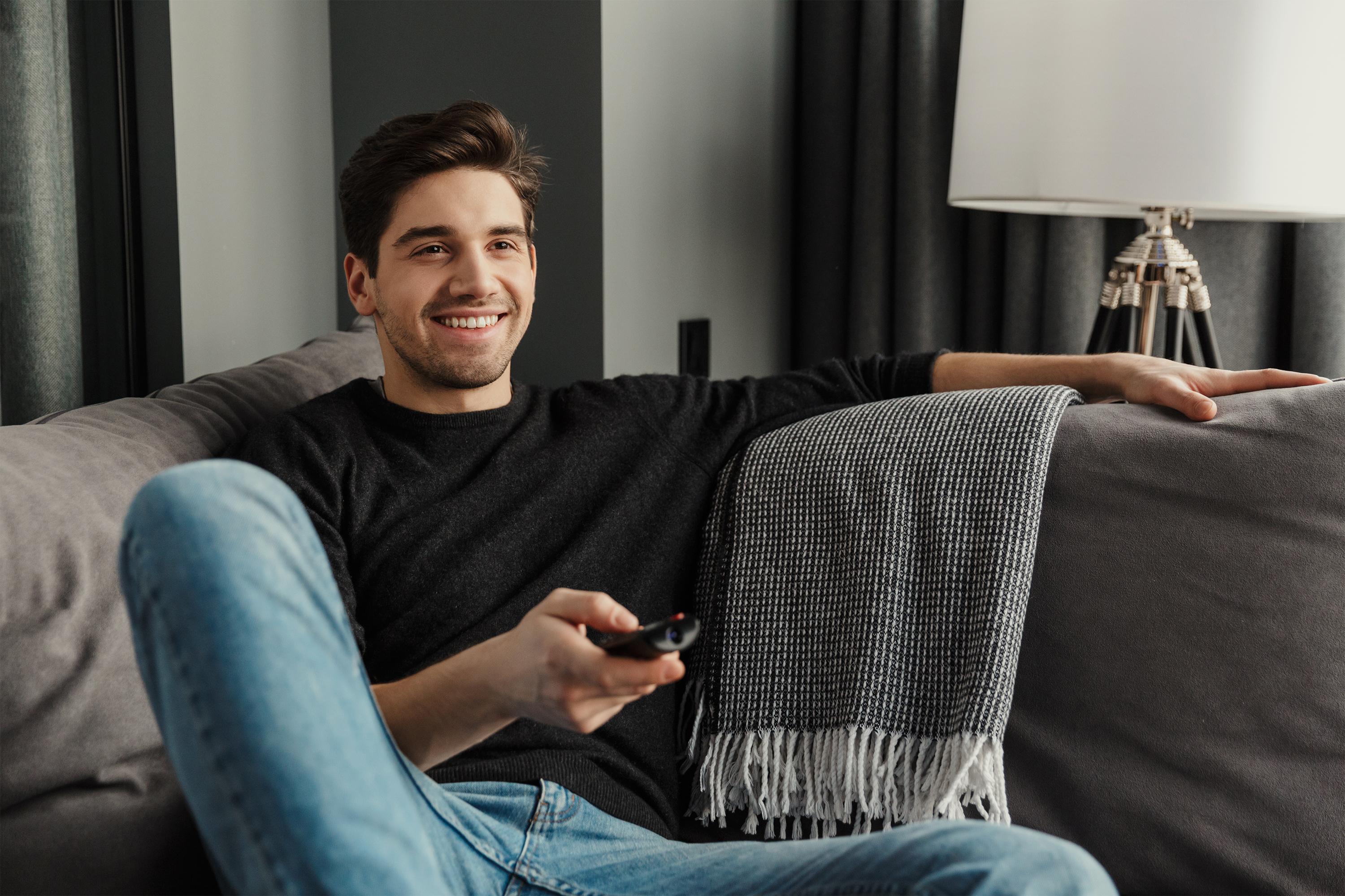 Man watching TV on sofa in living room
