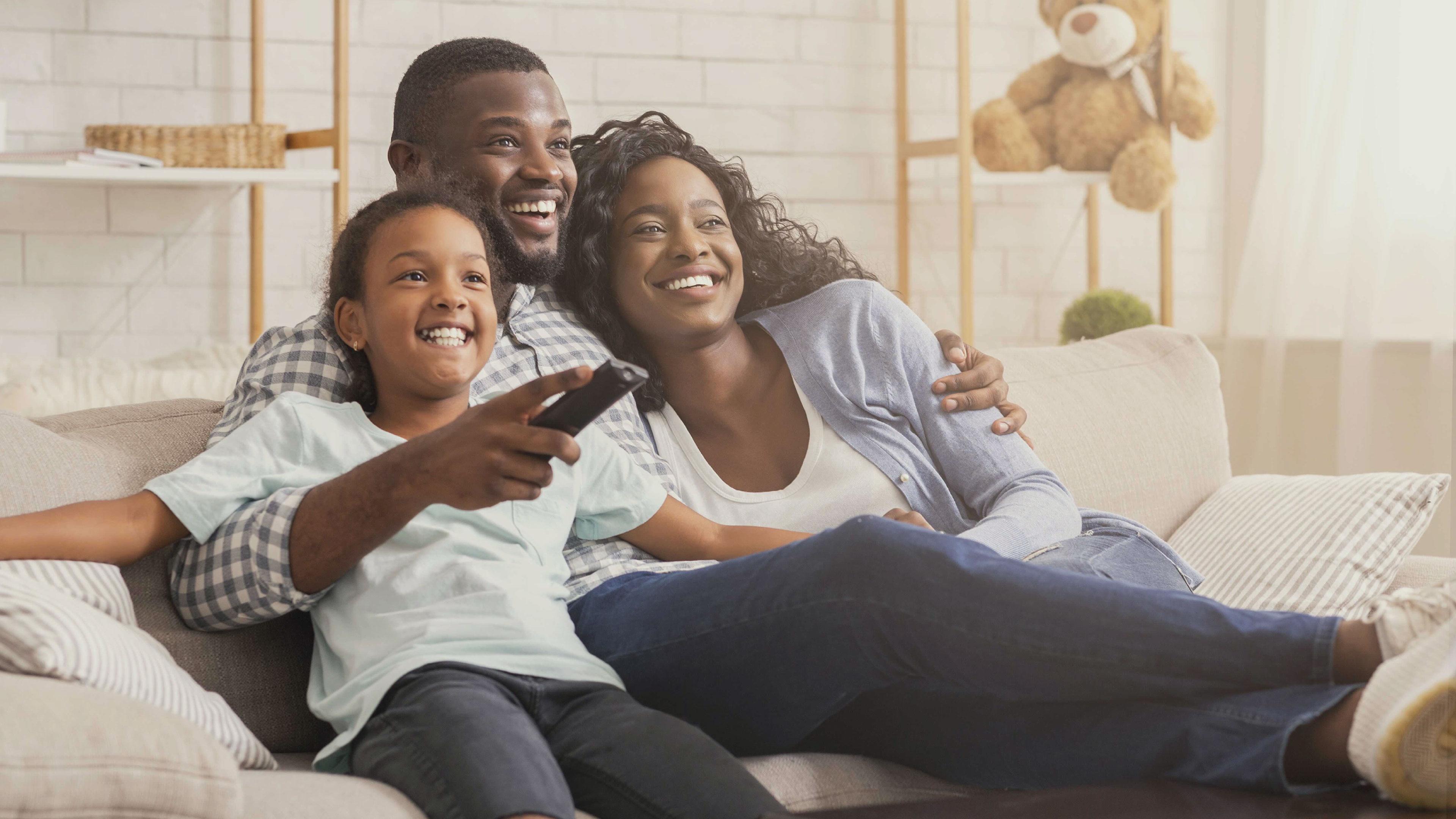 Black family watching TV on a sofa in living room