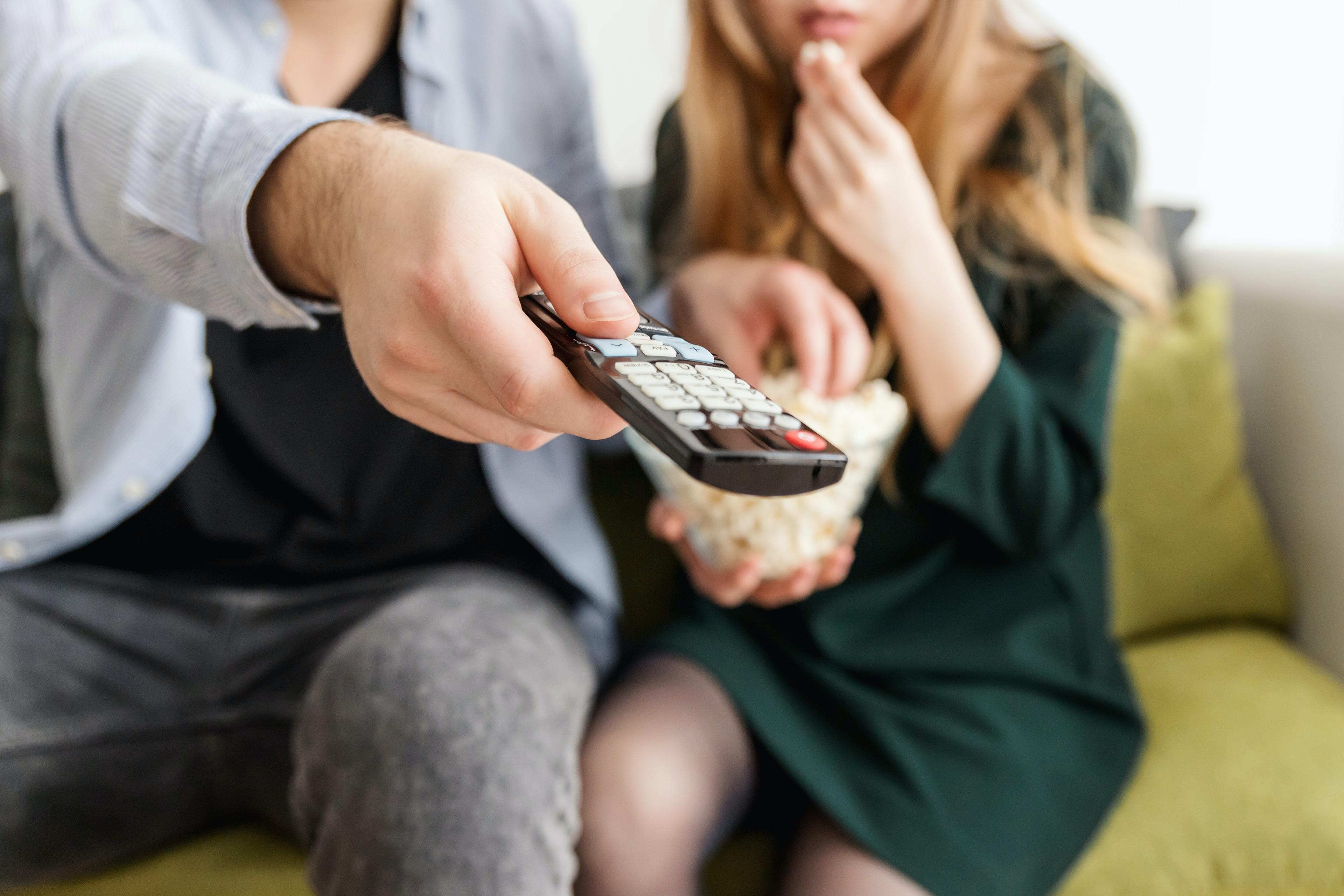 Couple watching TV on sofa in living room while having a snack