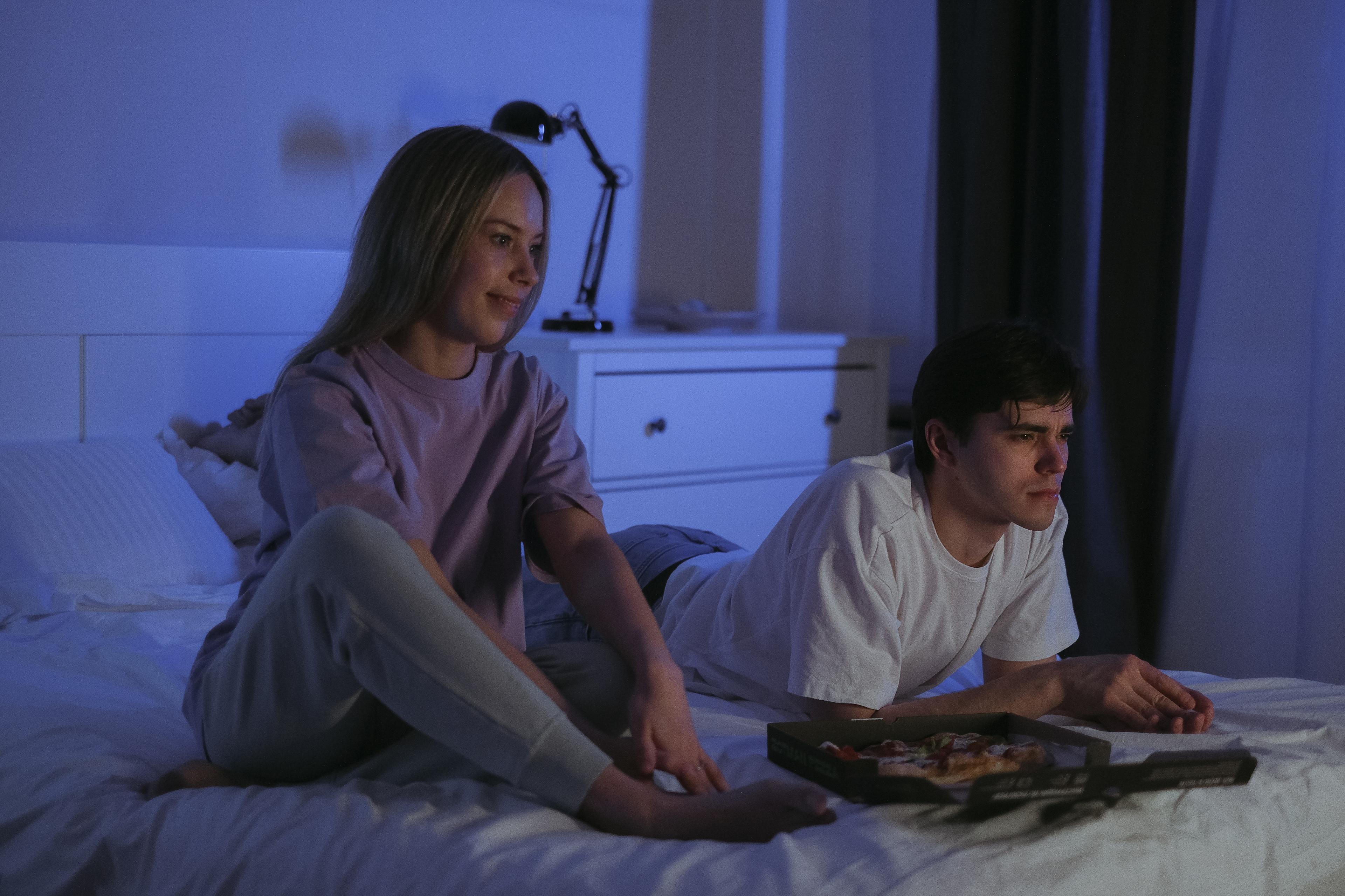 Couple watching TV on bed in bedroom