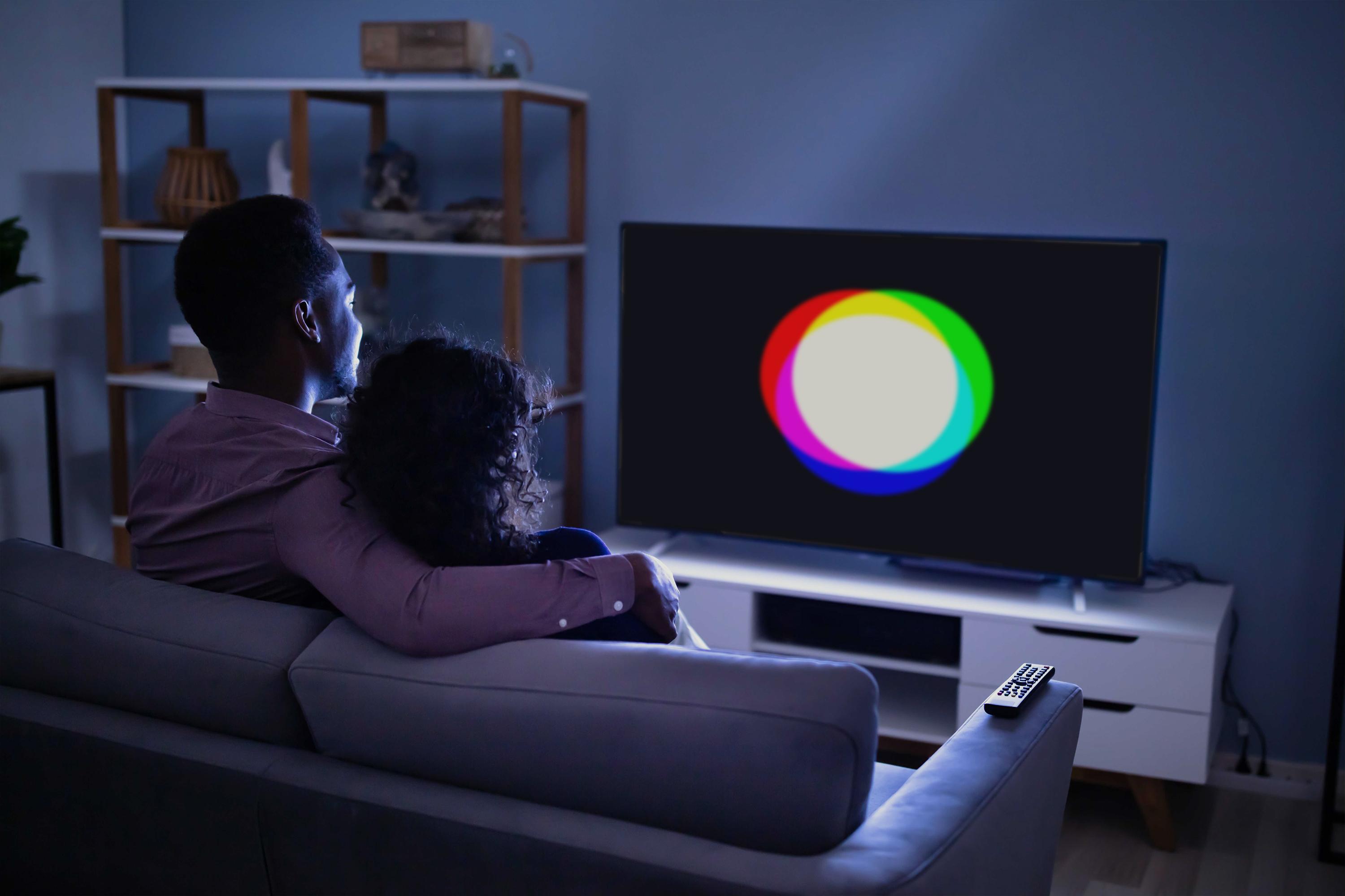 Couple watching TV in living room with Finecast logo on TV